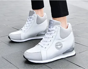 Detail view of stylish white and grey women's hidden wedge sneakers on grey pavement