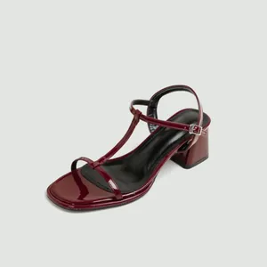 Detailweergave van elegante bordeauxrode laklederen T-strap sandalen met een blokhak