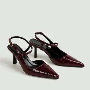 Dettaglio di tacchi a spillo bordeaux con elegante trama a coccodrillo.