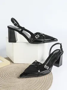 Dettaglio di eleganti sandali slingback in camoscio nero e vernice con tacco a blocco