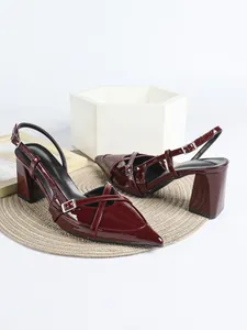 Dettaglio ravvicinato delle scarpe bordeaux in vernice con punta, tacco largo e fibbie
