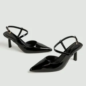 Dettaglio di tacchi a spillo in pelle verniciata nera con punta e cinturino slingback