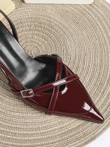 Dettaglio di eleganti décolleté a punta in vernice bordeaux con raffinati cinturini a fibbia.