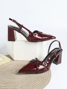 Dettaglio di eleganti décolleté slingback bordeaux in vernice con fibbie argentate