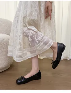 French style black square-toe ballet flats with bow detail worn with a lace dress