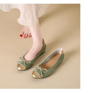Primo piano di eleganti ballerine in velluto verde con fiocco e punta dorata.