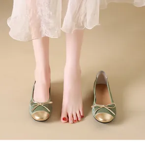 Primo piano di eleganti ballerine in velluto verde con fiocco oro e punta metallica