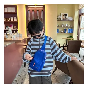 A young boy models a trendy blue canvas sling bag in a stylish modern cafe setting.