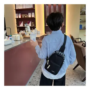 Boy's black fabric chest bag with fashion letter print in a stylish cafe setting