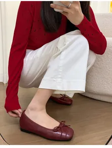 Detailed view of red French bow ballet flats with square toe worn by a model