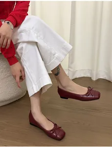 French style red bow ballet flats with square toe and soft leather worn by a model