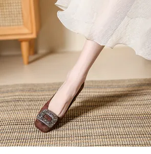 Close-up of brown suede square toe pumps with an elegant sparkling rhinestone buckle detail