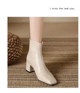 Close-up view of beige square-toe Chelsea boot with thick heel shown on a woven rug
