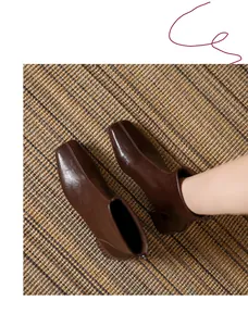 Top view of stylish brown square-toe ankle boots with chunky heel on woven rug