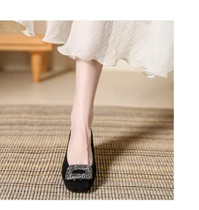 Close-up of black square-toe pumps with elegant rhinestone buckle on model