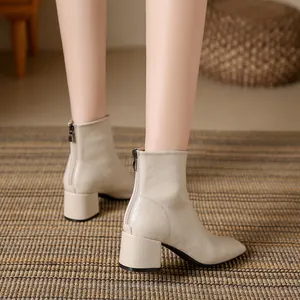 Elegant beige square-toe chunky heel ankle boots for women in a cozy room setting