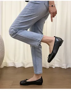 Elegante schwarze Ballerinas mit Schleife und eckiger Zehenpartie an einem Model in Jeans.
