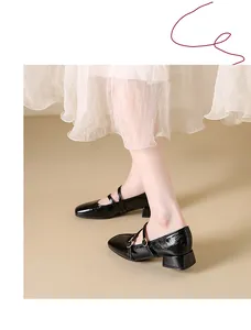 Detail view of glossy black square toe Mary Jane shoes with chunky heels and buckle straps