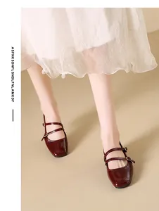 Detailed view of burgundy square-toe Mary Jane shoes worn with a white dress