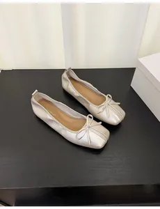 Detailed view of champagne metallic ballet flats with delicate bow and square toe