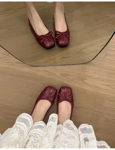 French style burgundy square toe ballet flats with bow detail on wooden floor