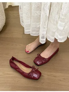 Detailaufnahme der eleganten weinroten Ballettschuhe mit eckiger Zehenpartie und Schleife