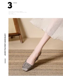 Elegant grey square-toe ballet flats with large metal buckle detail shown on a straw mat
