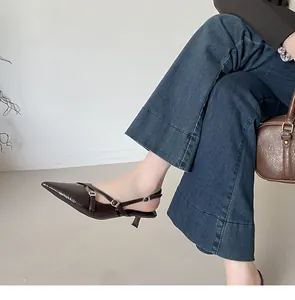 Detail van elegante donkerbruine slingback pumps met spitse neus en gespbandjes.