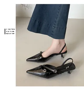Elegante zwarte slingback pumps met puntige neus en metalen gespen in detailweergave