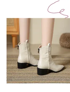 Gros plan de bottes de cow-boy en cuir crème à bout pointu avec fermeture éclair