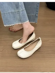 Close-up of beige soft leather ballet flats with split toe design on wooden floor
