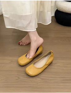Detail view of yellow split-toe tabi ballet flats on a warm wooden floor background.