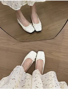 Detailaufnahme von cremefarbenen Ballettflats mit Schleife und eckiger Zehenpartie.