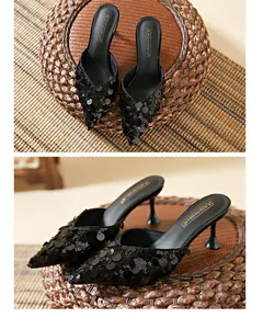 Detailed view of elegant black sequined pointed-toe kitten heel mules on a woven mat