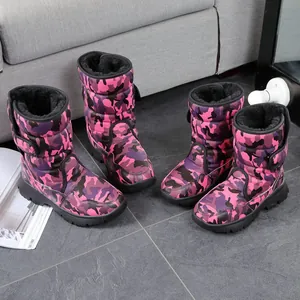 Durable pink and purple camouflage fur-lined snow boots for kids in a cozy indoor setting.