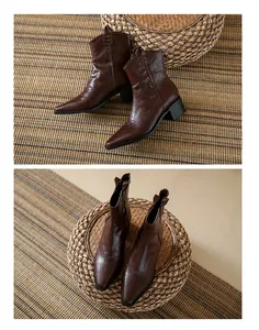 Détail de bottines cowboy vintage marron à bout pointu avec design en V sur tabouret.