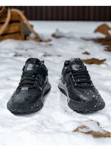 Detalle de botas de seguridad de invierno aisladas con forro polar cálido sobre suelo nevado.