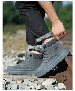 Nahaufnahme grauer hoher Sicherheitsstiefel mit warmem Fellfutter auf Außenbahngleisen
