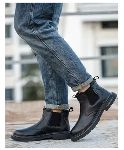 Primer plano de botas de trabajo de seguridad Chelsea negras con jeans al aire libre