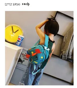 Kleinkind trägt einen blauen Dinosaurier-Rucksack mit niedlichen 3D-Zacken aus Stoff.