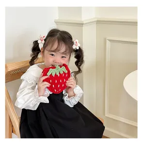 Schattig kind houdt een handgehaakte aardbeientas voor kinderen vast in een lichte kamer