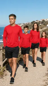 Family group wearing matching red long-sleeve athletic shirts on a sunny coastal walk