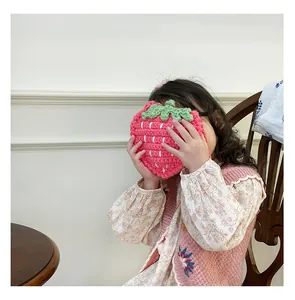 Schattige handgemaakte gehaakte aardbeientas voor kinderen, gedragen door kind.