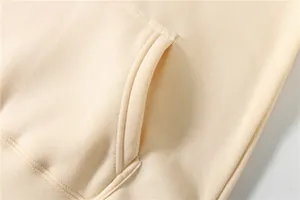 Macro view showing the reinforced stitching and pocket detail of a beige cotton hoodie