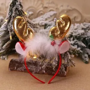 Close-up of a Christmas reindeer antler headband with golden horns and white fur trim on a log