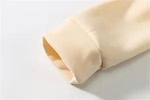 Detailed macro view of the elastic ribbed cuff on a premium soft cream-colored hoodie sleeve