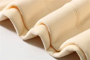 Macro detail of a cream-colored hoodie showing the soft fabric and ribbed cuff stitching.