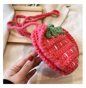 Dichtbij van een handgemaakte roze gehaakte aardbei crossbody tas vastgehouden in hand