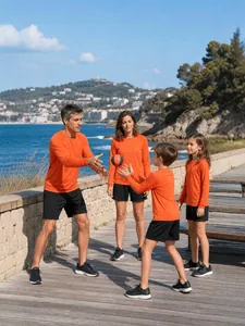 Active family wearing matching orange long-sleeve sports shirts on a scenic boardwalk