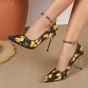 Detail view of stylish lemon print stiletto high heels with golden ankle straps.